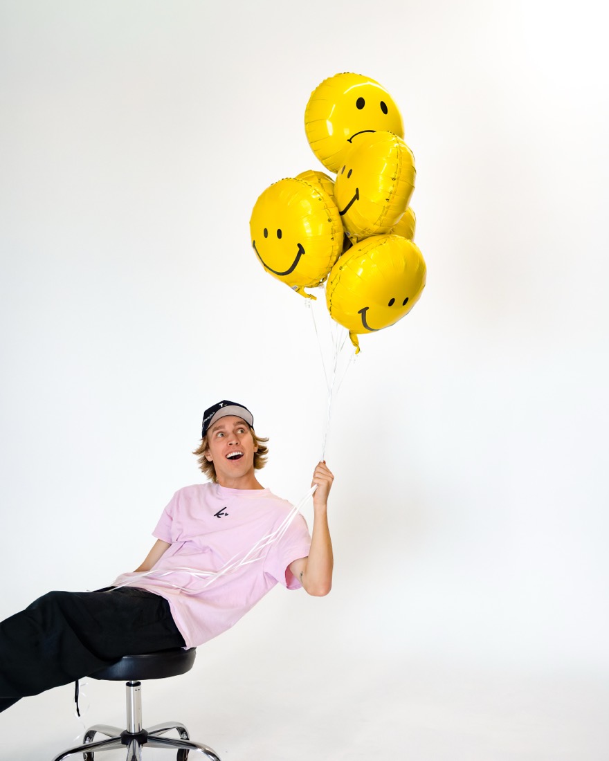 BBYFERG leaning back on a stool holding balloons